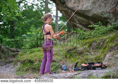 Woman Belays Her Partner Climber With Belaying Device And Rope. Climbers Helper Holding Equipment Fo
