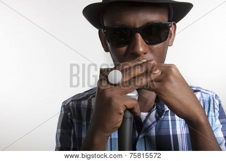 african man with glasses and hat play an harmonica 
