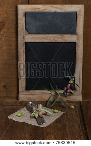 Blackboard With Olives And Tableware