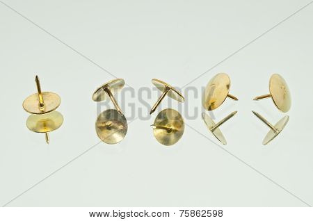 A Collection Of Five Lying Thumbtacks In Line