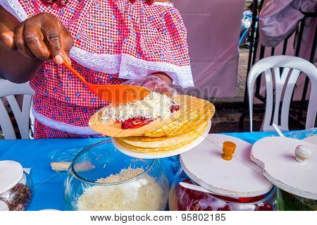 Closeup traditional Colombian streetsnack oblea being prepared adding white sauce top of jam and coc