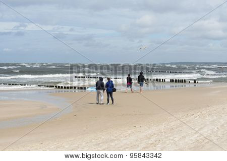 USTKA - JULY 10: Tourists walking along the beach on a cold summer day on 10 July 2015 in Ustka, Poland.