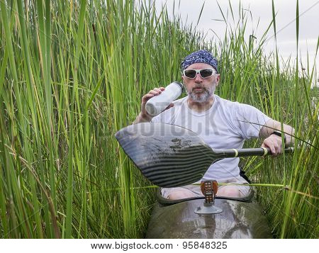 tired senior male paddler takes break from paddling a kayak and hydrating deep inside  reeds