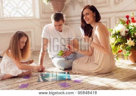 Beautiful family of tree playing  boad game on floor