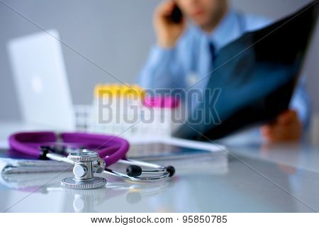 Medical doctor  sitting at table and looking patients roentgen