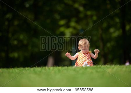 happy young baby child sittng on grass on beautiful summer day in park