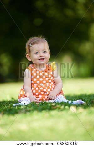 happy young baby child sittng on grass on beautiful summer day in park