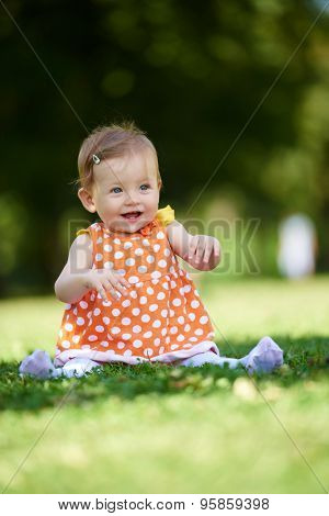happy young baby child sittng on grass on beautiful summer day in park