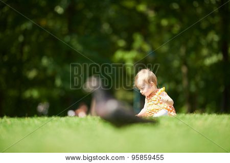 happy young baby child sittng on grass on beautiful summer day in park