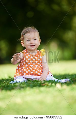 happy young baby child sittng on grass on beautiful summer day in park