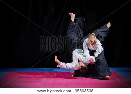 Fight between two aikido fighters on black