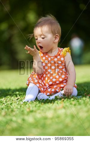 happy young baby child sittng on grass on beautiful summer day in park