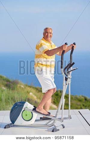 healthy senior man working out on gym treadmill machine at modern home terace with ocean view