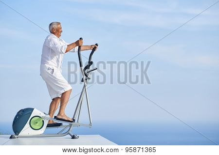 healthy senior man working out on gym treadmill machine at modern home terace with ocean view