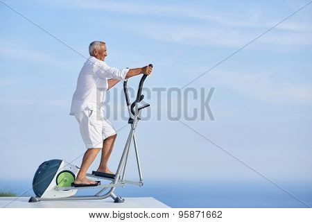 healthy senior man working out on gym treadmill machine at modern home terace with ocean view