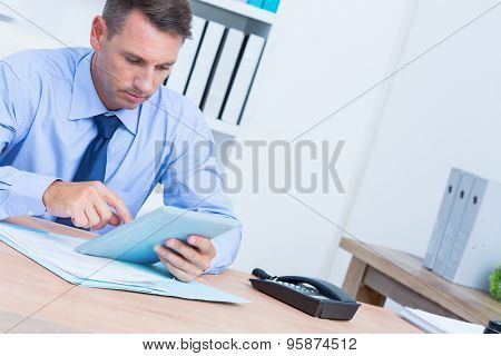 S erious businessman using digital tablet in the office