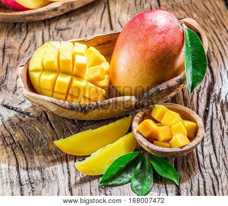 Mango fruit and mango cubes on the wooden table.