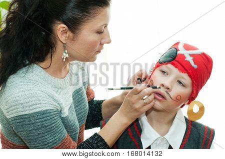 woman paints the boy's face before the concert