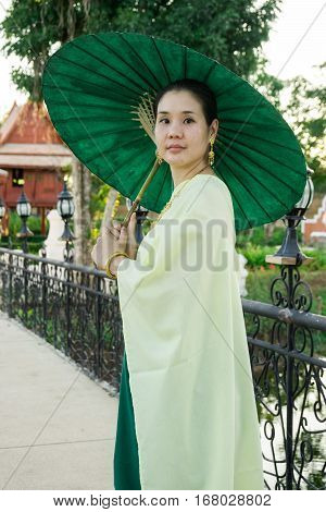 Portrait of woman dressing in Thai traditional costume using an umbella