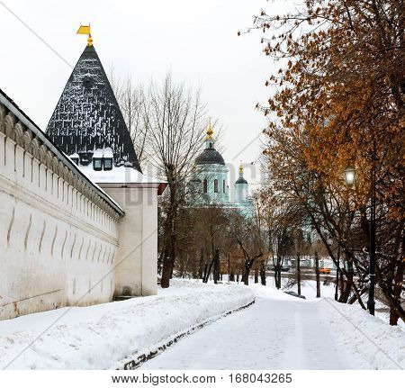 The wall and tower of Spaso-Andronikov Monastery, Temple of St. Sergius of Radonezh in the background. Moscow, Russia in winter.