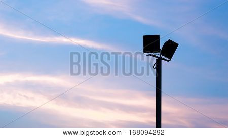 Spotligth lamp and light concept - Silhouette of outdoor spotlight lamp on pole with evening sky and copy space