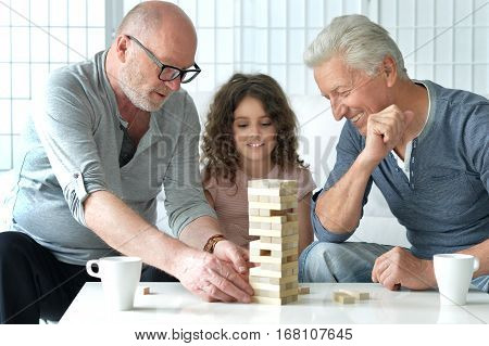 two mature men plaing jenga with granddaughter