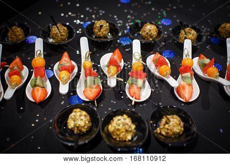 Fruit coloured desserts on the spoons close-up and small stars on the table