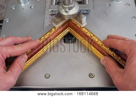 Craftsman working on frame in frameshop. Professional framer hand holding frame angle. Top view.