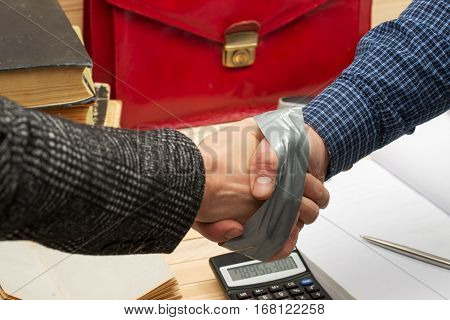 Business concept. Business partners handshaking after signing contract. Pertnership. On a wooden table books, documents, calculator, red briefcase