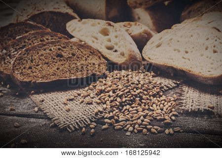 Plenty of sliced bread background. Bakery and grocery concept. Fresh, healthy whole grain sliced sorts of rye and white loaves, sprinkled flour on sackcloth and rustic wood table, food closeup.