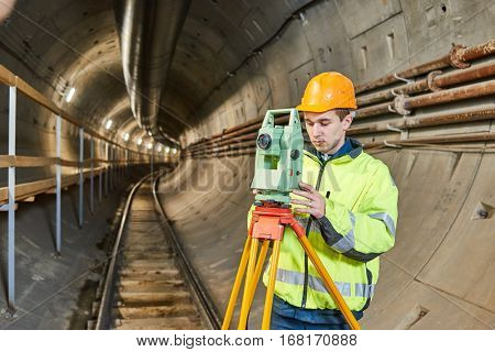 Surveyor with theodolite level at underground railway tunnel construction work