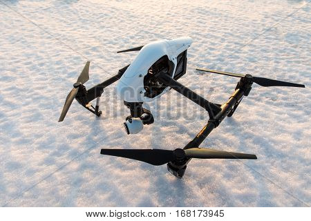White drone with digital camera standing on snow in winter.