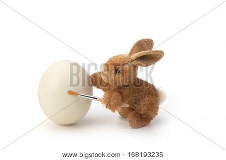 Easter Rabbit decorates an egg on a white background