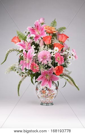 Roses and Lilia flowers in vase on grey background