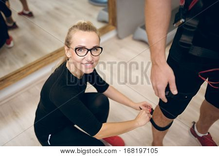 Happy Woman Kneeling For Fasten Belt On Man Leg