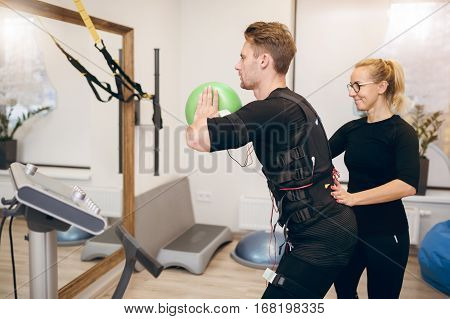 Sportsman Doing Ems Training With Coach In Front Of Mirror