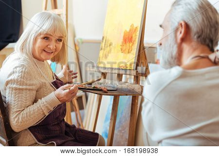 Inspirational communication. Male and female talented professional artists talking to each other while sitting in painting class and working.