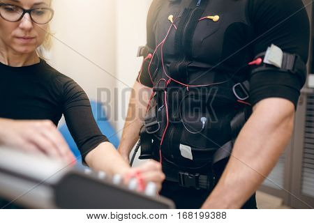 Sportsman In Full Ems Suit Standing Next To Ems Device