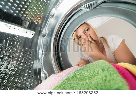 Close-up Of Young Woman Inserting Stinky Clothes In Washing Machine