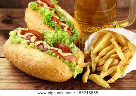 Hot Dogs With Glass Of Beer With French Fries On Wooden Board