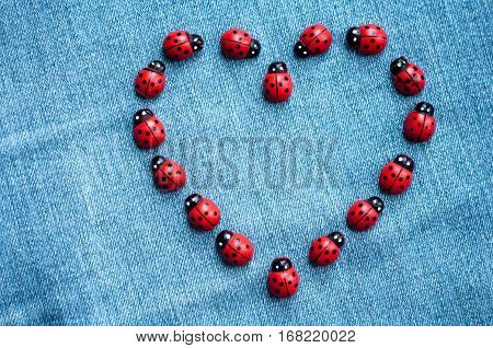 A group of red wooden ladybugs forming heart on the blue background