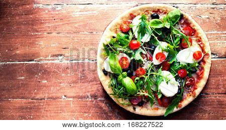 Hot pizza with meat basil and mozarella cheese on a dark background top view. Pizza on the rustic wooden table with copy space
