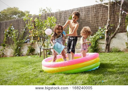 Children Having Fun In Garden Paddling Pool