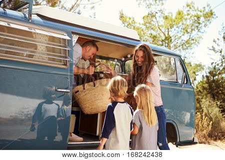 Family packing up their camper van for a road trip vacation