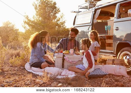 Family having a picnic beside their camper van, full length