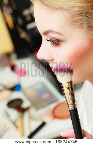 Visage concept. Close up woman getting make up on cheeks. Applying blush with brush.