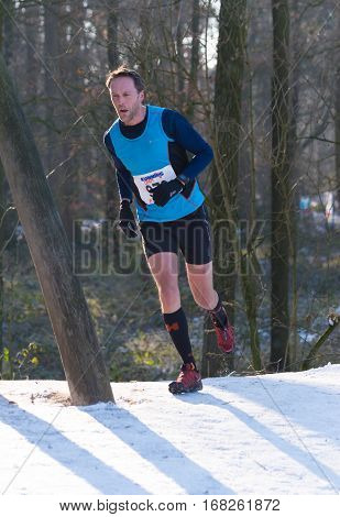 OLDENZAAL NETHERLANDS - JANUARY 22 2017: Unknown athlete runs up a hill during a cross run in a forest