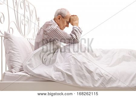 Depressed senior lying in bed with his head down isolated on white background