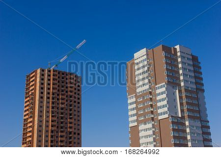 Crane and building construction site against blue sky.