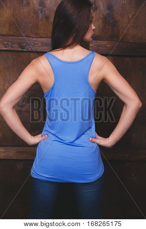 Young woman wearing blank blue top with area for your logo or design, mock-up of template blue top, wooden wall in the background